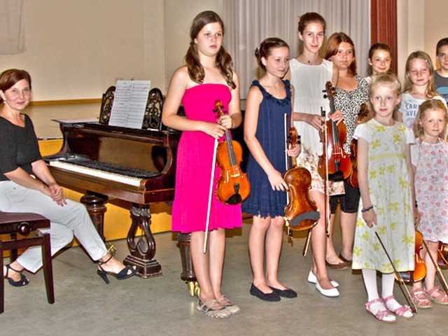 Kinder stehen mit Geigen im Konzertsaal